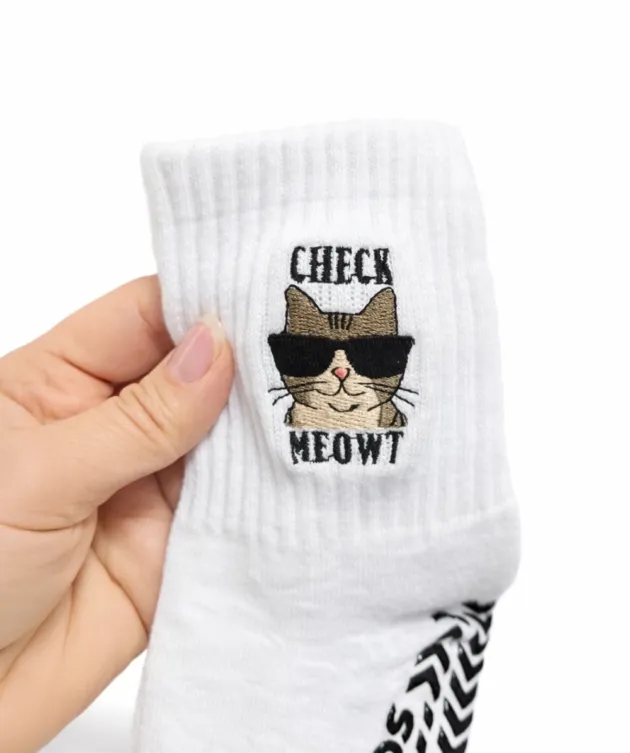 White Treads grip sock with anti-slip sole and “Check Meowt” cat design held in hand