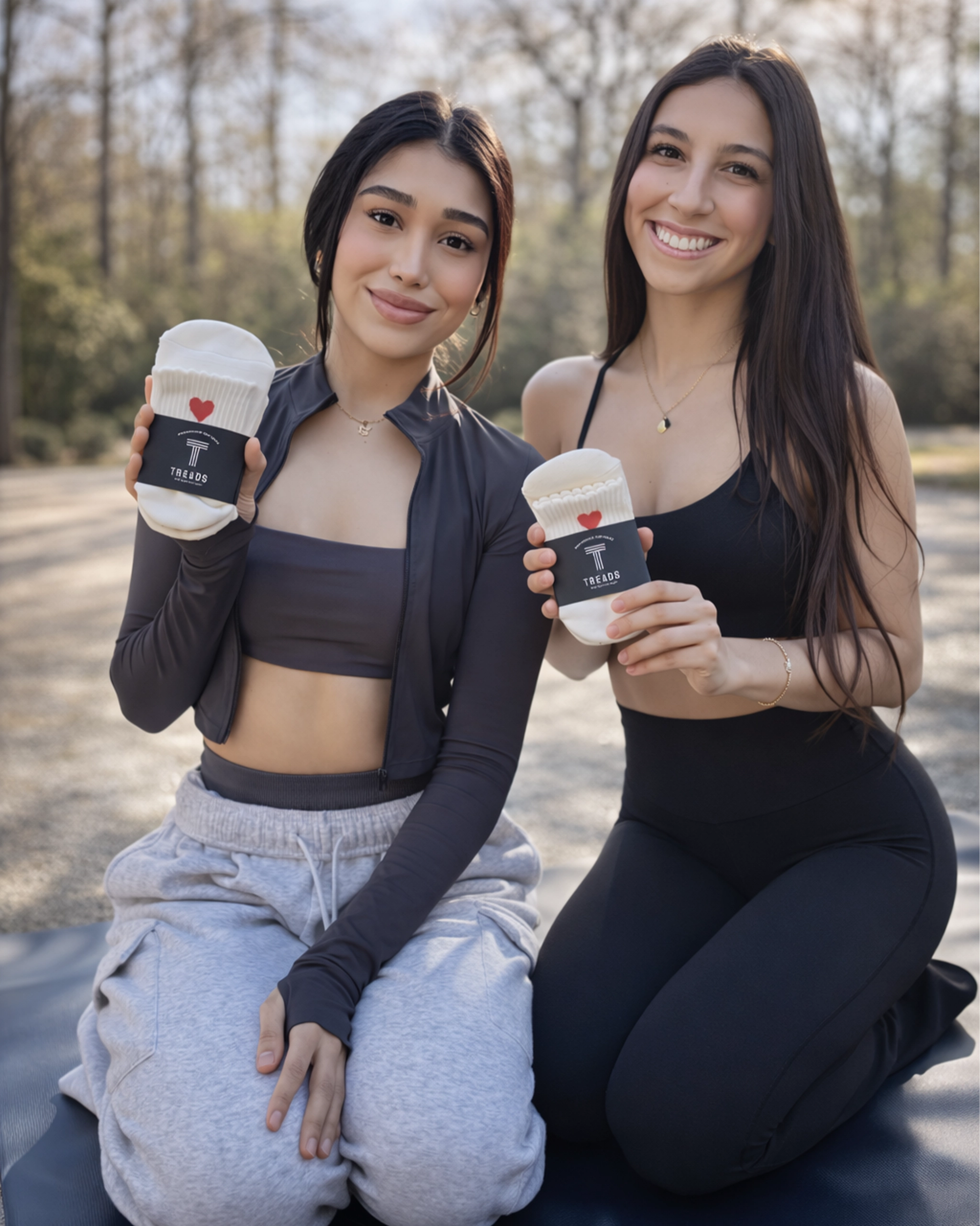 Two women holding Treads grip socks outdoors, showcasing white anti-slip athletic socks for fitness and everyday wear